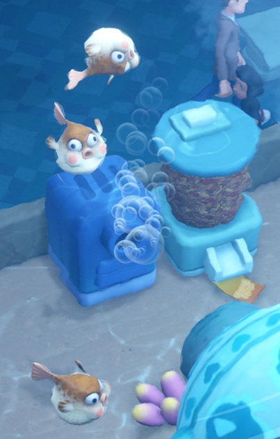 Drie Floating Fishes zwemmen in hun Aquarium. De bovenste van de drie zwemt ondersteboven. Op de achtergrond zijn een Filter en een Flake Food Dispenser zichtbaar.